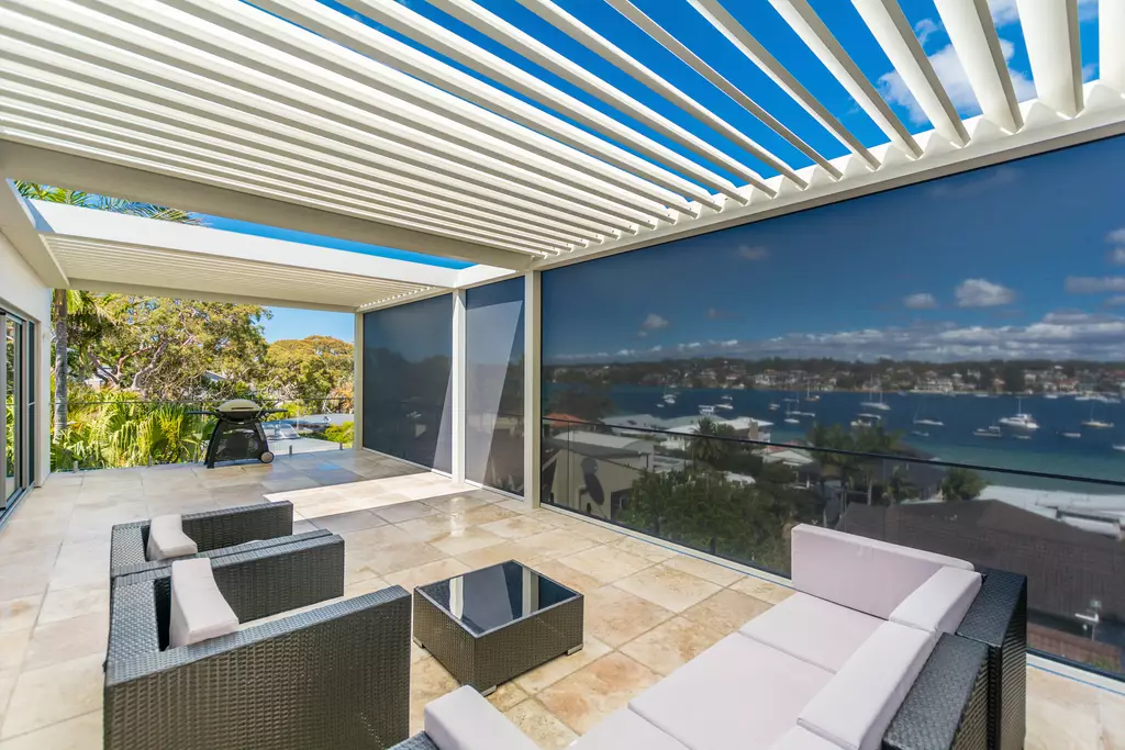 Pérgola bioclimática Algarve adosada a villa con lamas orientables y paneles laterales zip-screen.